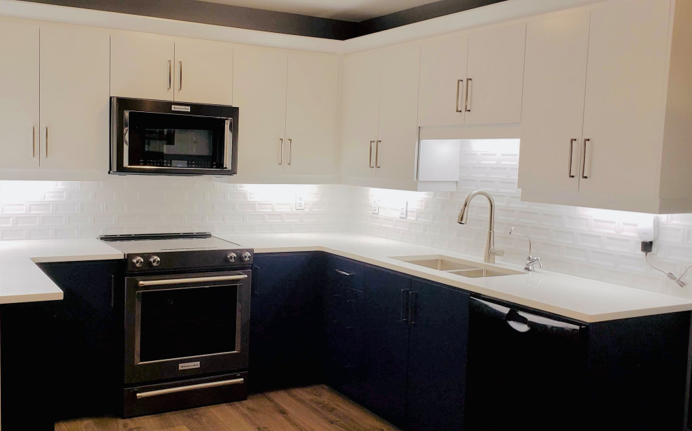 Open concept kitchen - transitional u-shaped open concept kitchen idea with an undermount sink, flat-panel cabinets, white cabinets, quartzite countertops, white backsplash, porcelain backsplash, no island and white countertops