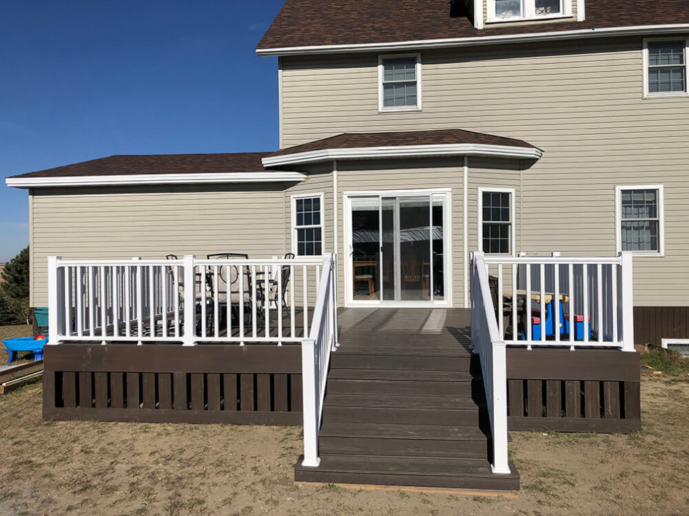 This is an example of a large country backyard and ground level deck in Other with with skirting and mixed railing.