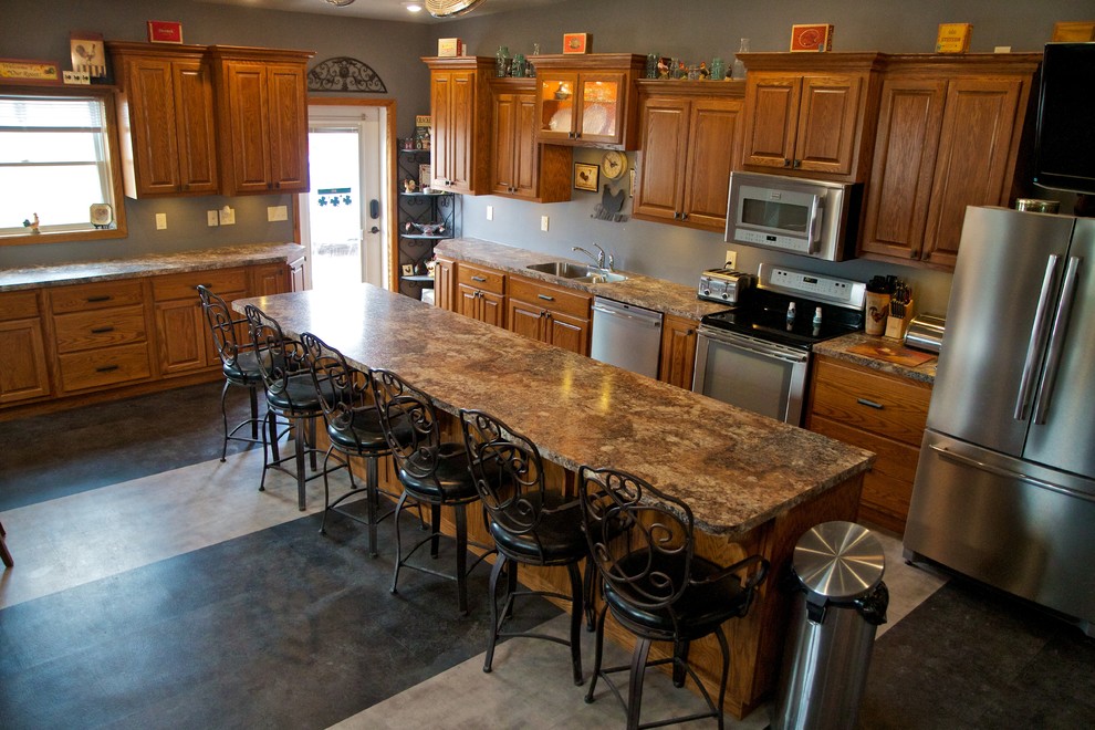 Open concept kitchen - large l-shaped open concept kitchen idea with an undermount sink, raised-panel cabinets, light wood cabinets, laminate countertops, stainless steel appliances and an island