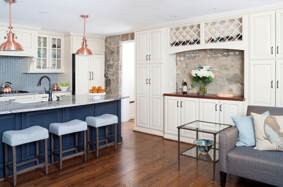 This is an example of a mid-sized traditional single-wall open plan kitchen in DC Metro with a farmhouse sink, raised-panel cabinets, granite benchtops, blue splashback, panelled appliances, with island, white cabinets, ceramic splashback and dark hardwood floors.