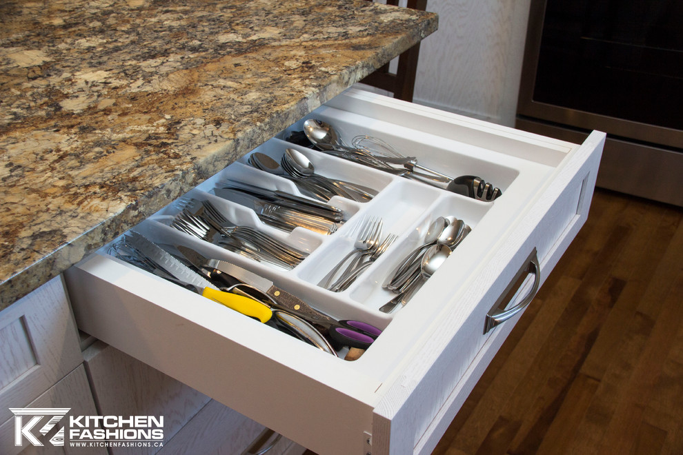 Example of a mid-sized transitional l-shaped medium tone wood floor open concept kitchen design with a drop-in sink, shaker cabinets, white cabinets, laminate countertops, white backsplash, subway tile backsplash, stainless steel appliances and an island