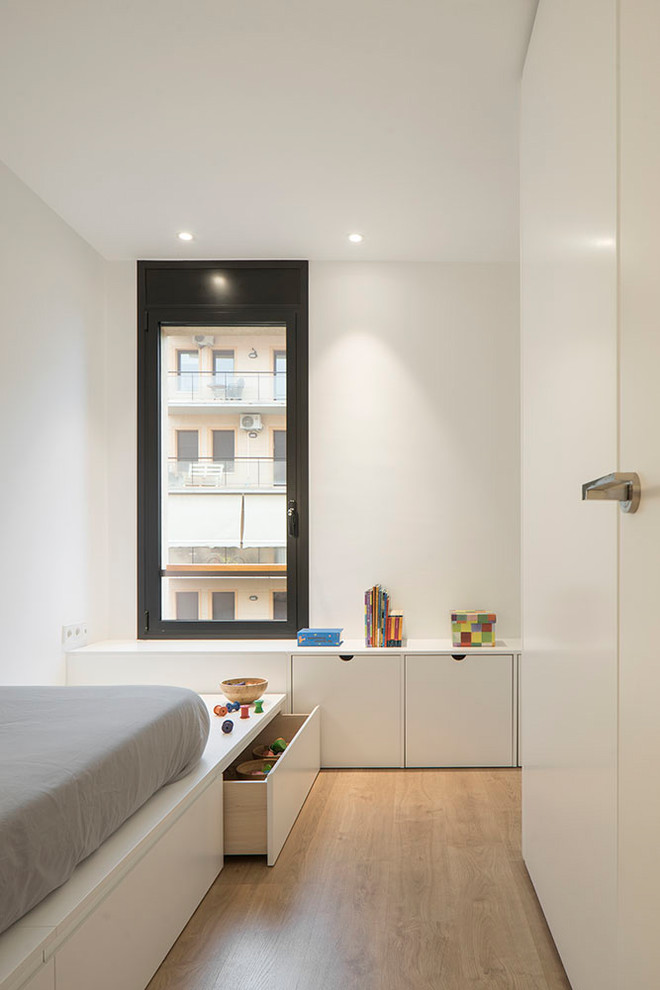 This is an example of a mid-sized contemporary gender-neutral kids' bedroom for kids 4-10 years old in Barcelona with white walls, medium hardwood floors and brown floor.