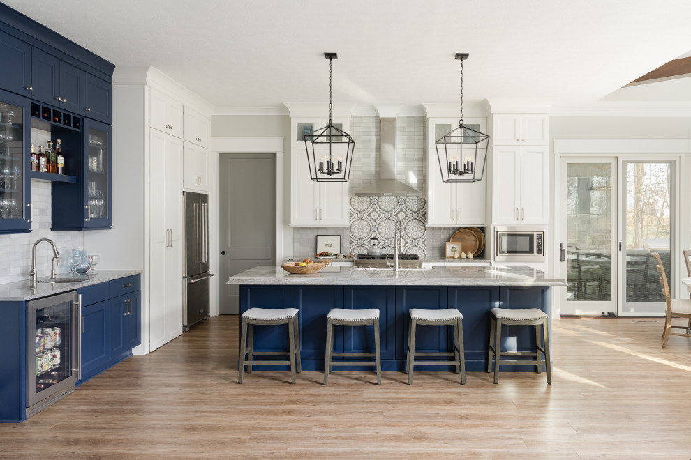 This is an example of a mid-sized transitional galley eat-in kitchen in Indianapolis with an undermount sink, glass-front cabinets, blue cabinets, granite benchtops, white splashback, granite splashback, stainless steel appliances, medium hardwood floors and with island.