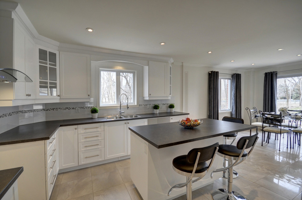 Inspiration for a mid-sized modern u-shaped separate kitchen in Montreal with a double-bowl sink, shaker cabinets, white cabinets, laminate benchtops, white splashback, porcelain splashback, porcelain floors and with island.