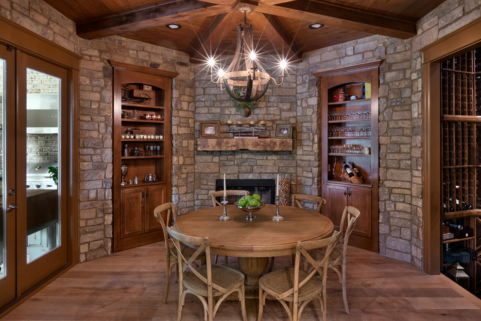 Design ideas for a large country separate dining room in Other with medium hardwood floors, brown floor and a stone fireplace surround.
