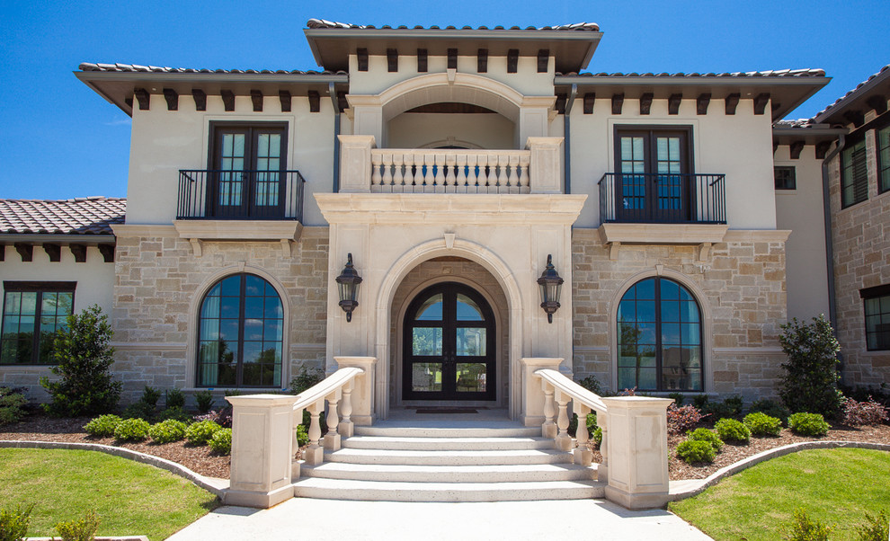 This is an example of a two-storey stucco beige house exterior in Dallas with a tile roof.