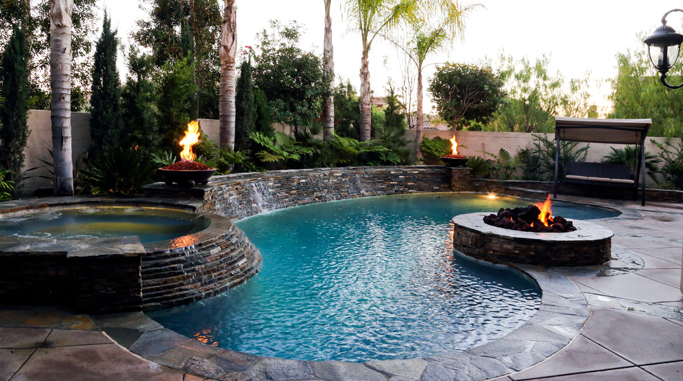 Photo of a mid-sized traditional backyard kidney-shaped lap pool in Orange County with a water feature and concrete slab.