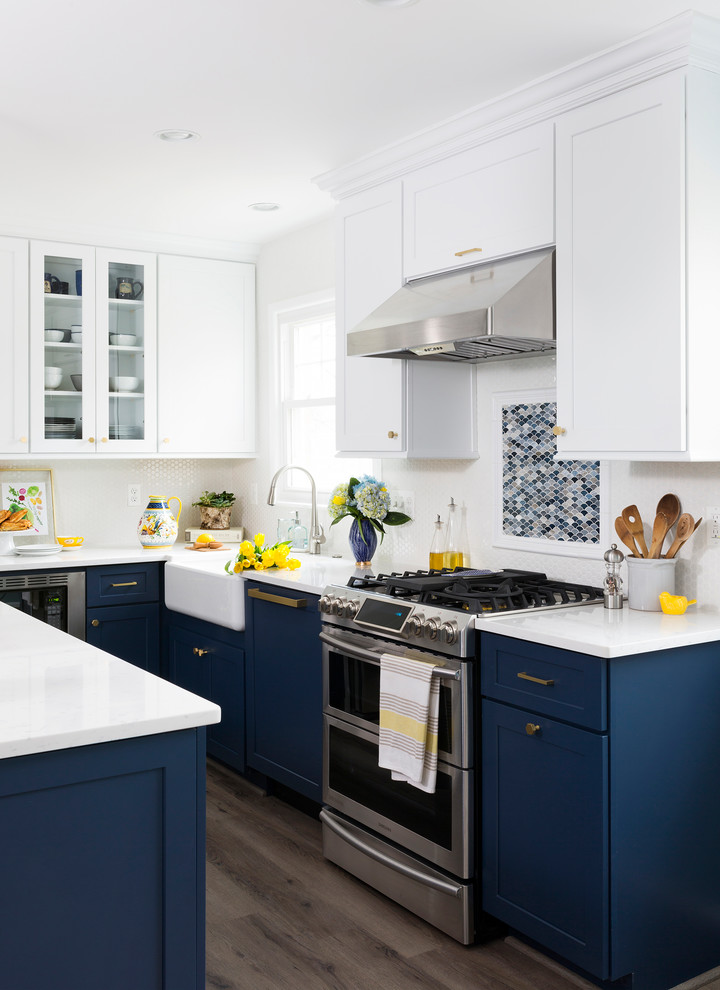 Mid-sized transitional l-shaped kitchen in Other with a farmhouse sink, shaker cabinets, blue cabinets, quartz benchtops, white splashback, with island, medium hardwood floors and brown floor.