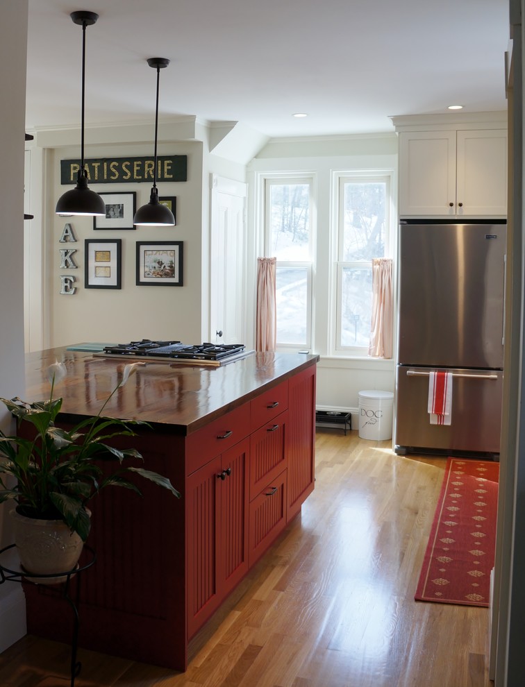 Inspiration for a small rustic l-shaped light wood floor and beige floor enclosed kitchen remodel in Boston with an undermount sink, recessed-panel cabinets, granite countertops, white backsplash, subway tile backsplash, stainless steel appliances, an island, white cabinets and black countertops