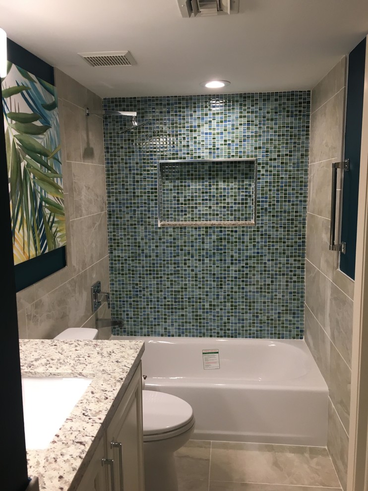 Design ideas for a mid-sized tropical 3/4 bathroom in Boston with raised-panel cabinets, white cabinets, an alcove tub, a shower/bathtub combo, a two-piece toilet, blue tile, mosaic tile, cement tiles, an undermount sink, granite benchtops, beige floor, a shower curtain and white benchtops.