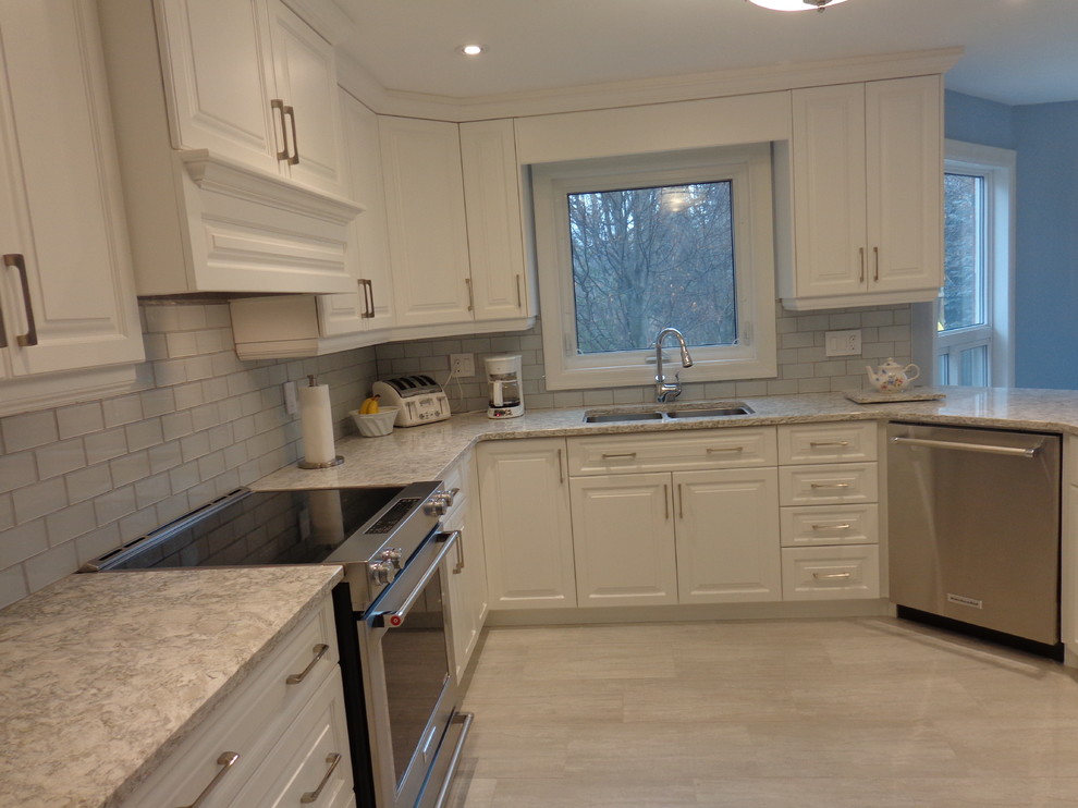 Example of a mid-sized transitional l-shaped porcelain tile eat-in kitchen design in Toronto with an undermount sink, raised-panel cabinets, white cabinets, quartz countertops, gray backsplash, glass tile backsplash and stainless steel appliances