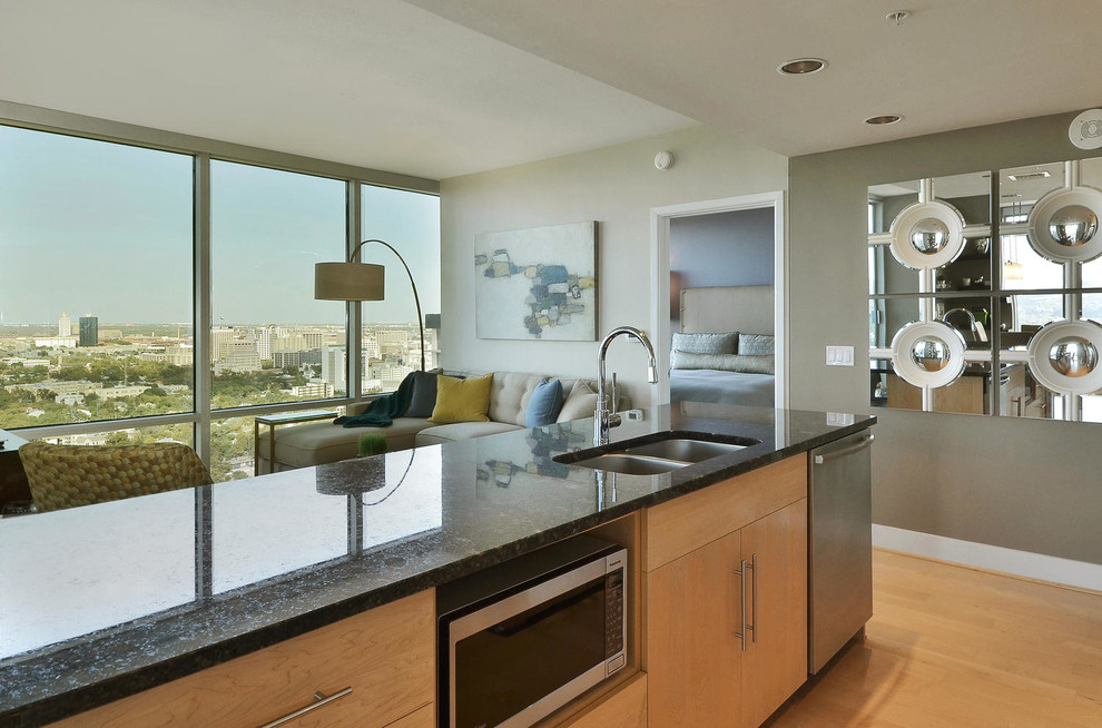 Small transitional galley light wood floor open concept kitchen photo in Austin with a double-bowl sink, flat-panel cabinets, light wood cabinets, granite countertops, beige backsplash, mosaic tile backsplash, stainless steel appliances and an island