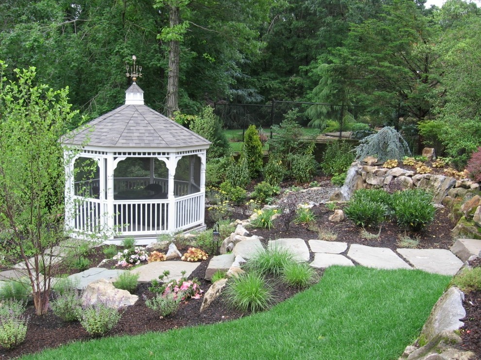 This is an example of a mid-sized tropical partial sun backyard stone water fountain landscape in New York for summer.