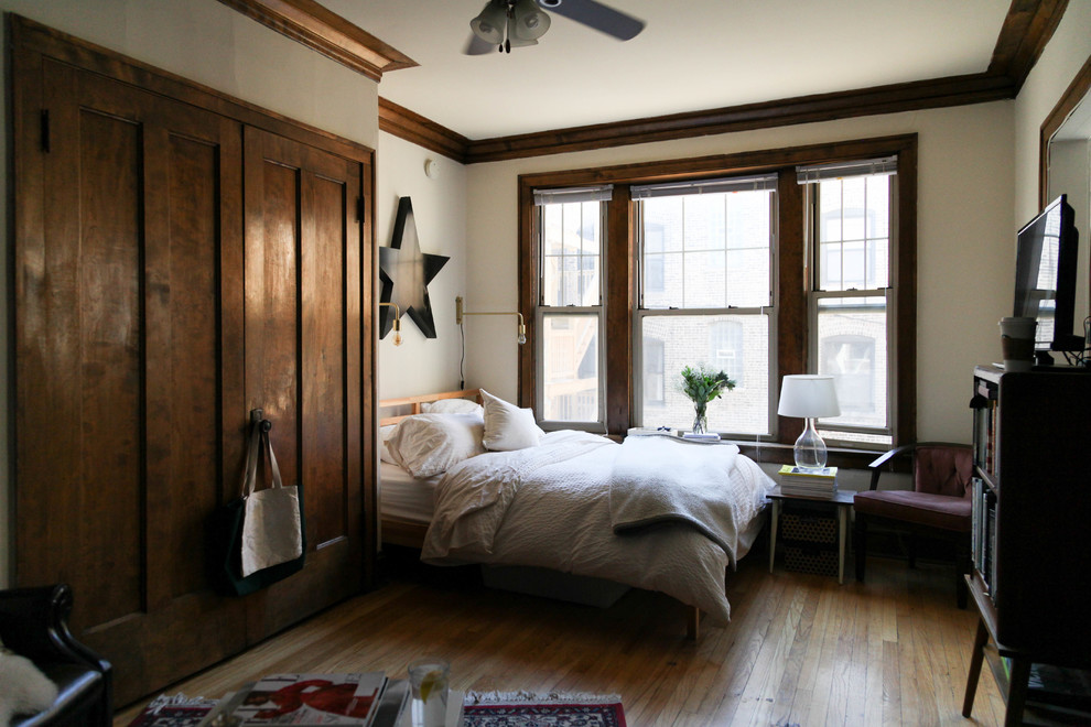 Photo of a transitional bedroom in Chicago with white walls, medium hardwood floors and brown floor.