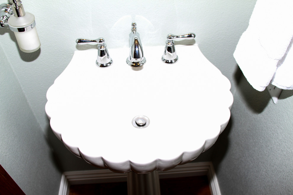 Example of a small transitional 3/4 medium tone wood floor and brown floor bathroom design in Orange County with a one-piece toilet, green walls and a pedestal sink