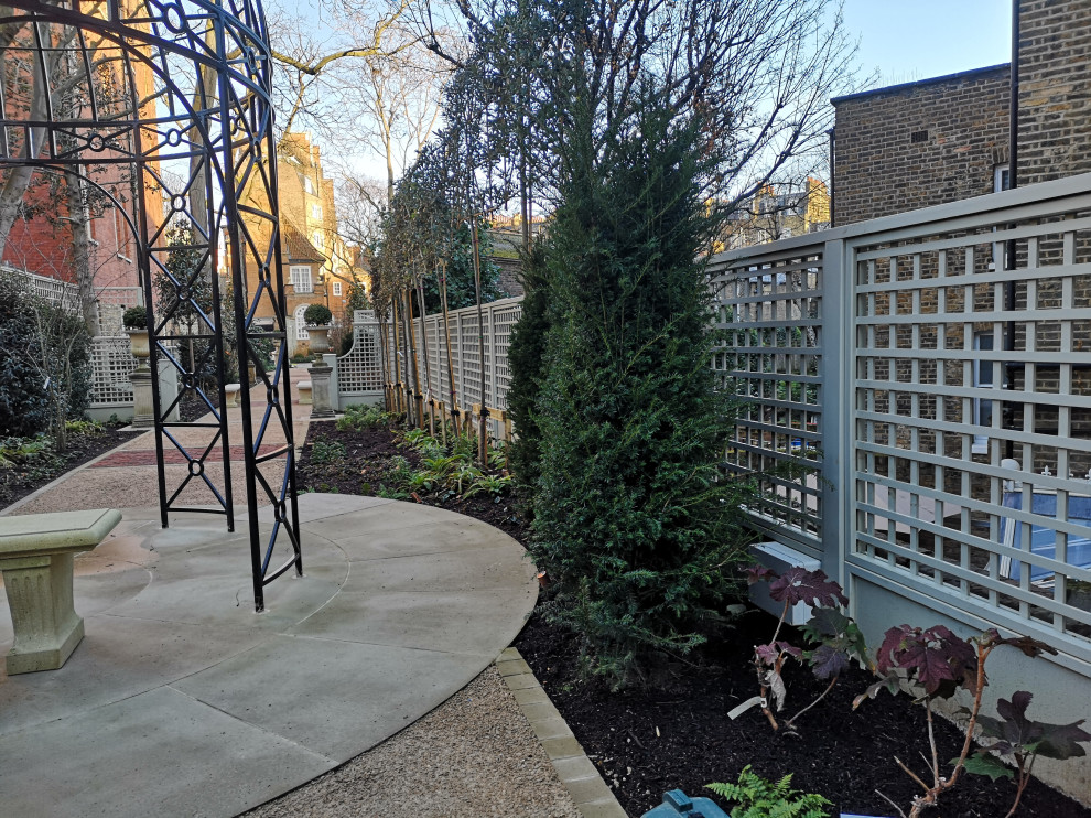 Contemporary back formal garden for spring in London with a living wall and a wood fence.