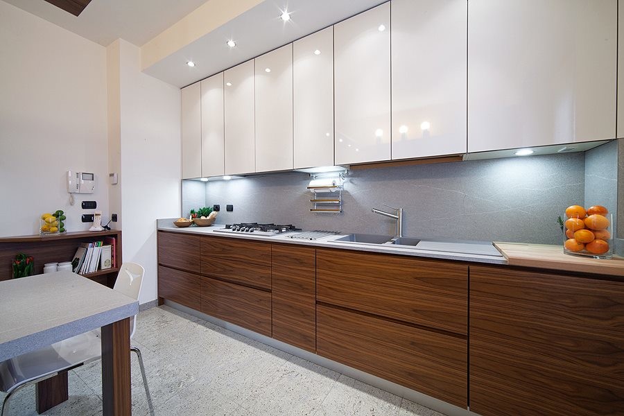 Design ideas for a large modern single-wall separate kitchen in Milan with an integrated sink, flat-panel cabinets, dark wood cabinets, solid surface benchtops, grey splashback, stainless steel appliances and porcelain floors.