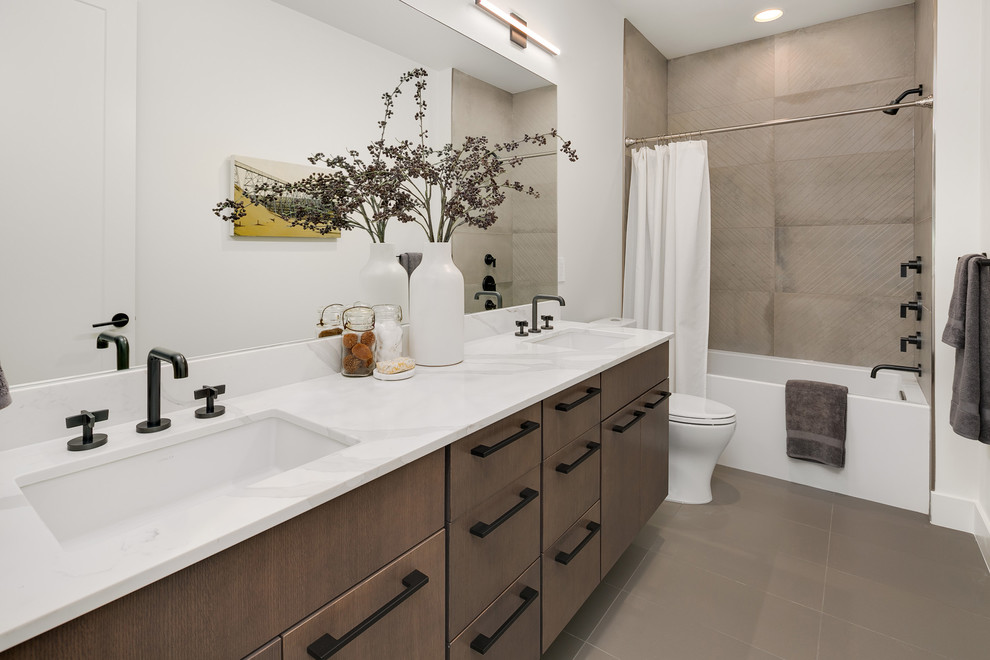 This is an example of a mid-sized contemporary bathroom in Seattle with flat-panel cabinets, grey cabinets, a shower/bathtub combo, a two-piece toilet, gray tile, white walls, an undermount sink, engineered quartz benchtops, grey floor, a shower curtain and white benchtops.