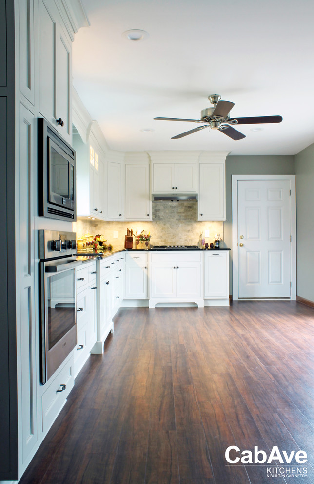 Mid-sized transitional l-shaped vinyl floor and brown floor eat-in kitchen photo with an undermount sink, recessed-panel cabinets, white cabinets, quartz countertops, beige backsplash, ceramic backsplash, stainless steel appliances and no island