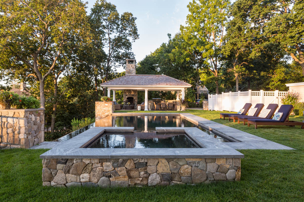 Design ideas for a large traditional backyard rectangular infinity pool in Portland Maine with a pool house and concrete slab.
