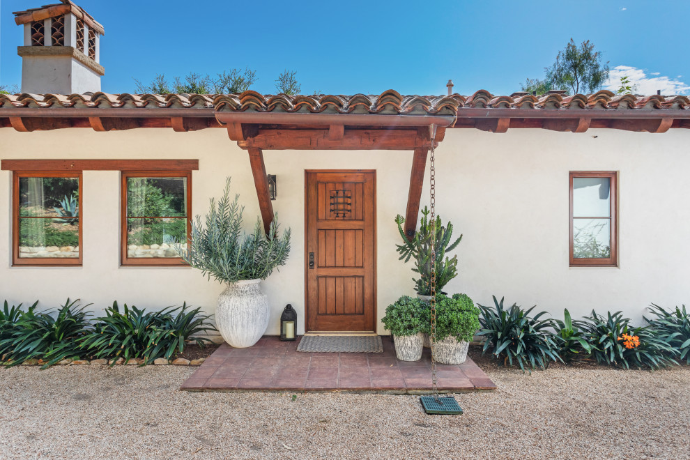 Inspiration pour une façade de maison beige méditerranéenne en stuc de taille moyenne et de plain-pied avec un toit en tuile et un toit rouge.
