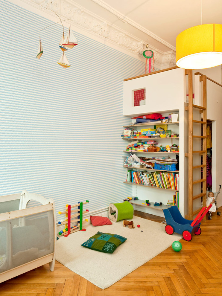 Mid-sized traditional gender-neutral kids' room in Berlin with blue walls and medium hardwood floors.