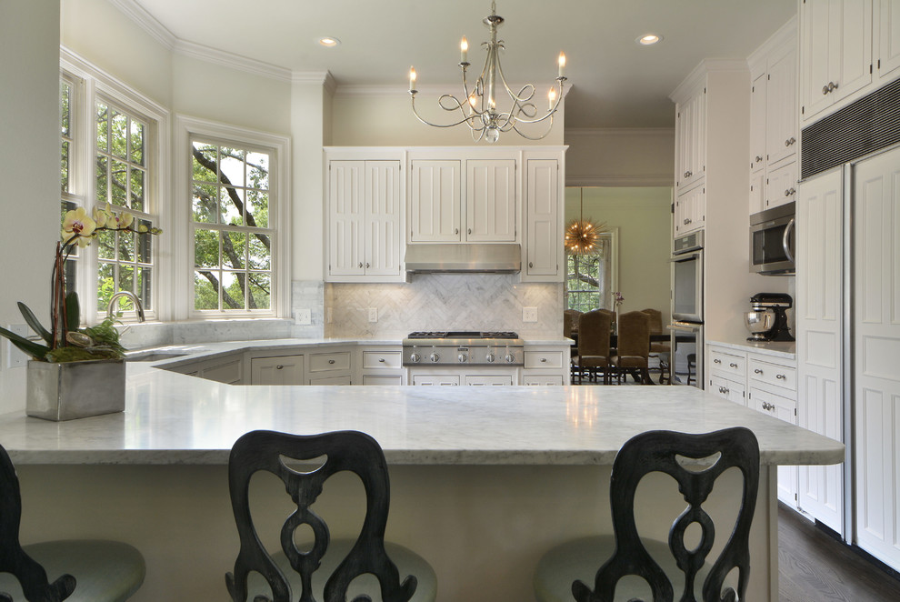 Inspiration for a mid-sized traditional u-shaped separate kitchen in Austin with an undermount sink, recessed-panel cabinets, white cabinets, white splashback, stainless steel appliances, dark hardwood floors, a peninsula, marble benchtops and stone tile splashback.