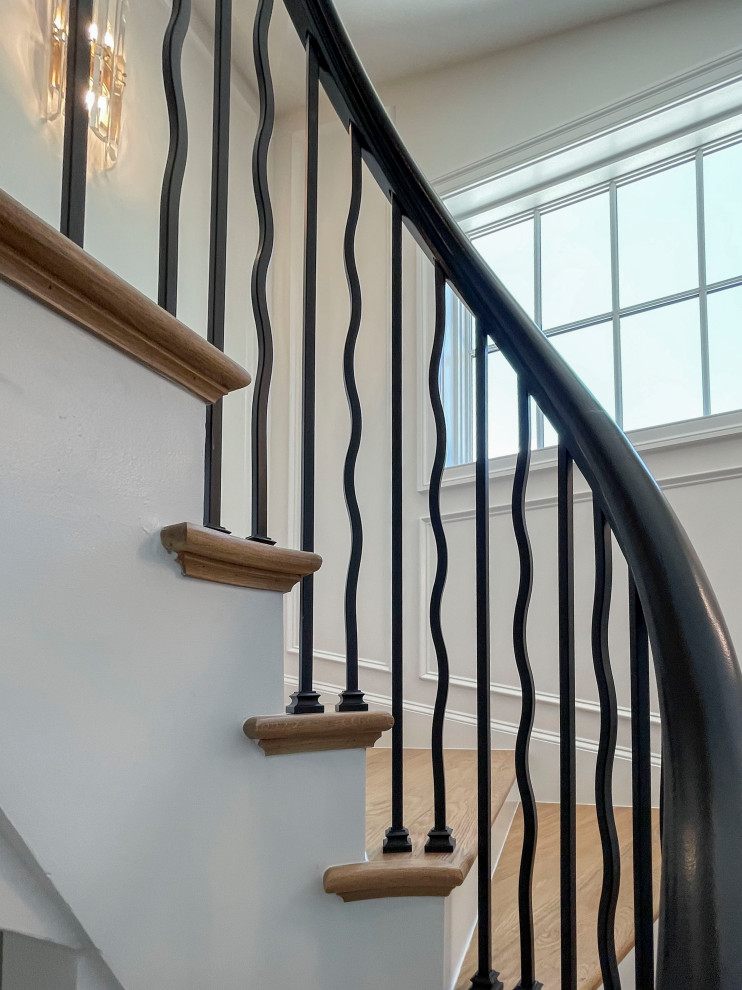 Large traditional wood floating mixed railing staircase in DC Metro with painted wood risers and wainscoting.