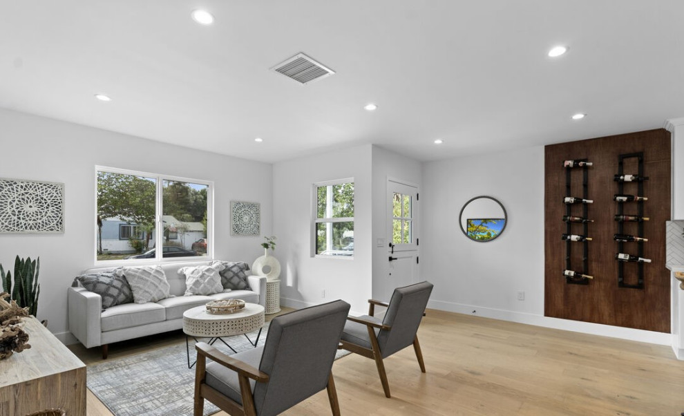 Источник вдохновения для домашнего уюта: гостиная комната среднего размера в современном стиле с белыми стенами, светлым паркетным полом, телевизором на стене и коричневым полом