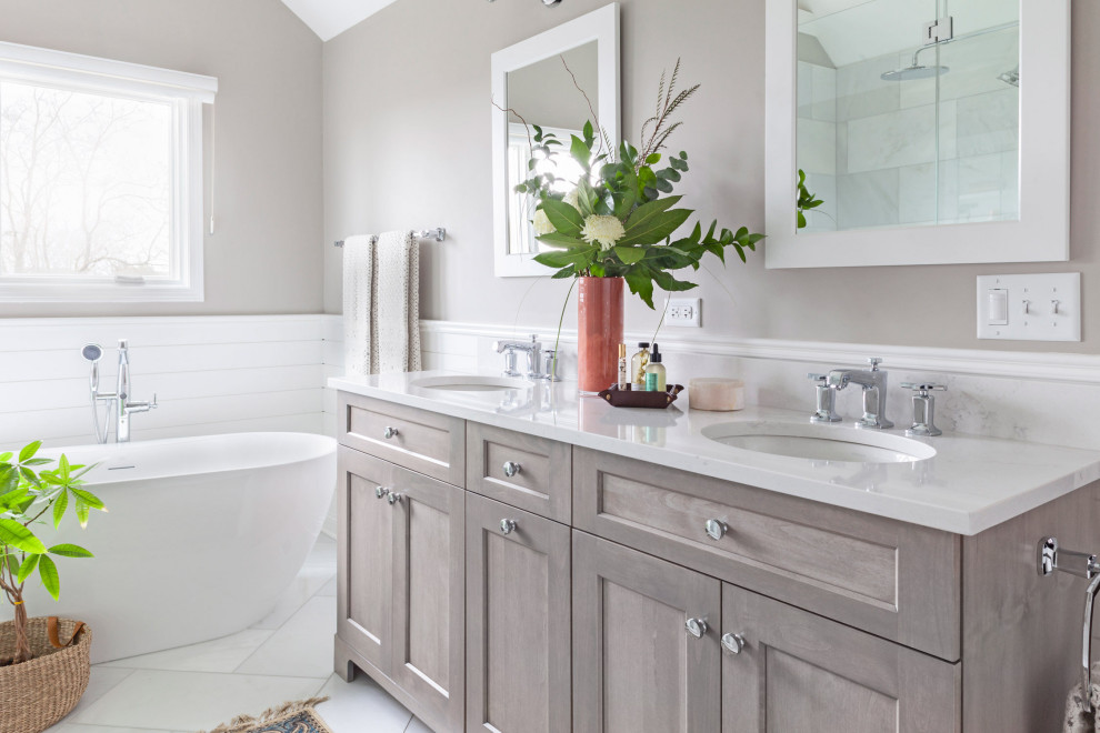 Mid-sized country master bathroom in Other with flat-panel cabinets, beige cabinets, a freestanding tub, an alcove shower, white tile, stone tile, grey walls, a drop-in sink, marble benchtops, white floor, a hinged shower door, white benchtops, a niche, a double vanity and a freestanding vanity.
