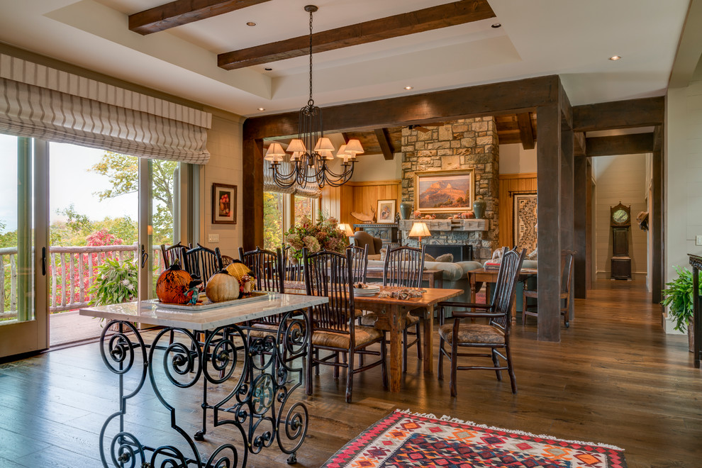Design ideas for a large country open plan dining in Other with beige walls, dark hardwood floors, a standard fireplace and a stone fireplace surround.