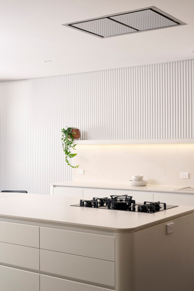Bild på ett stort minimalistiskt vit vitt kök, med en dubbel diskho, släta luckor, vita skåp, bänkskiva i kvarts, vitt stänkskydd, svarta vitvaror, skiffergolv, en köksö och svart golv
