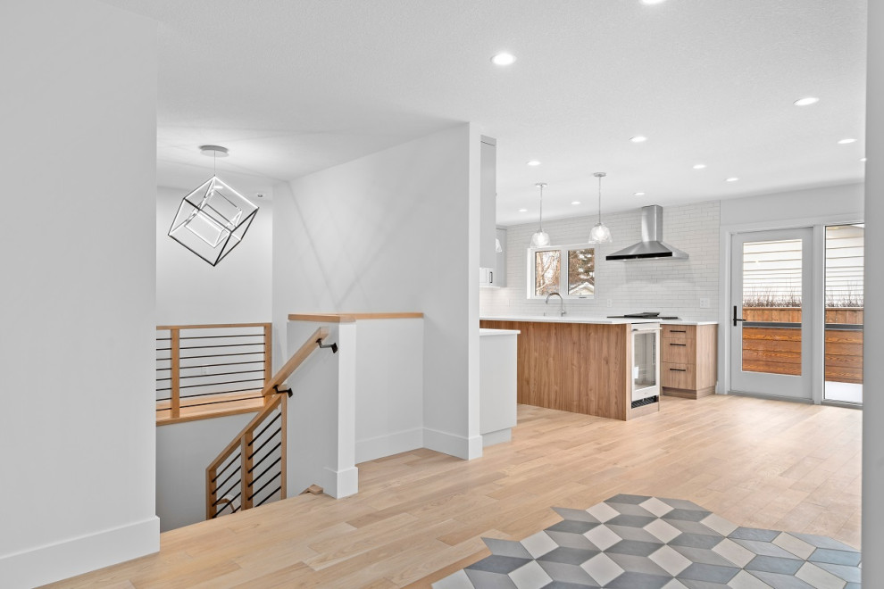 Small transitional l-shaped open concept kitchen photo in Calgary with flat-panel cabinets, light wood cabinets, quartz countertops, white backsplash, ceramic backsplash, stainless steel appliances, an island and white countertops
