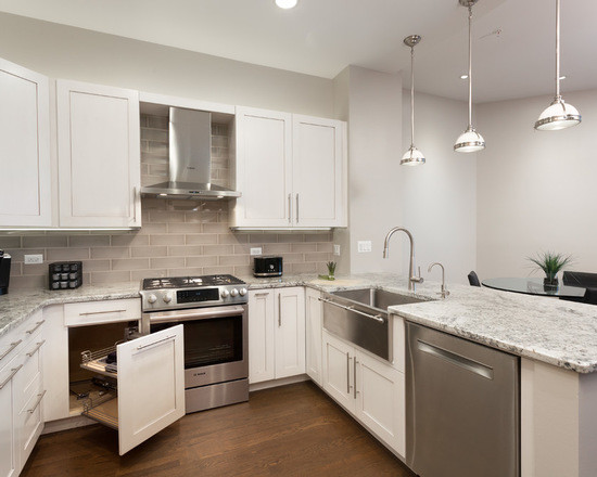Mid-sized transitional u-shaped eat-in kitchen in Chicago with a farmhouse sink, shaker cabinets, white cabinets, marble benchtops, beige splashback, subway tile splashback, stainless steel appliances, medium hardwood floors and no island.