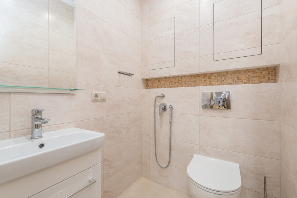 This is an example of a medium sized contemporary ensuite bathroom in Other with flat-panel cabinets, white cabinets, an alcove bath, a shower/bath combination, a wall mounted toilet, beige tiles, beige walls, ceramic flooring, an integrated sink, beige floors, an enclosed toilet, a single sink and a floating vanity unit.