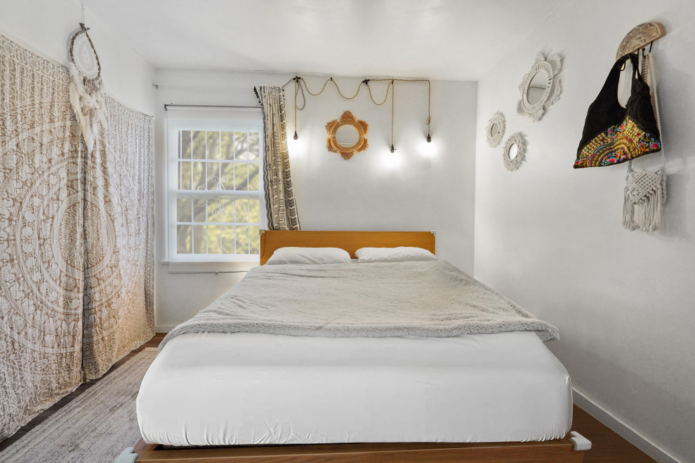 Esempio di una camera degli ospiti mediterranea di medie dimensioni con pareti bianche, pavimento in legno massello medio e pavimento multicolore