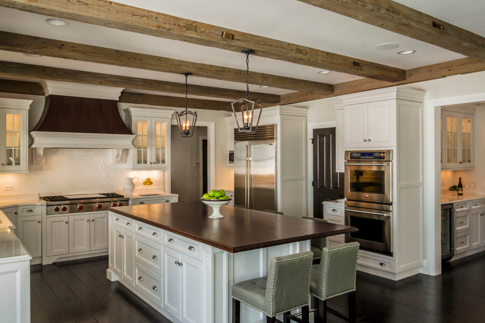Example of a large transitional l-shaped dark wood floor eat-in kitchen design in Chicago with an undermount sink, recessed-panel cabinets, white cabinets, quartz countertops, white backsplash, ceramic backsplash, stainless steel appliances and an island