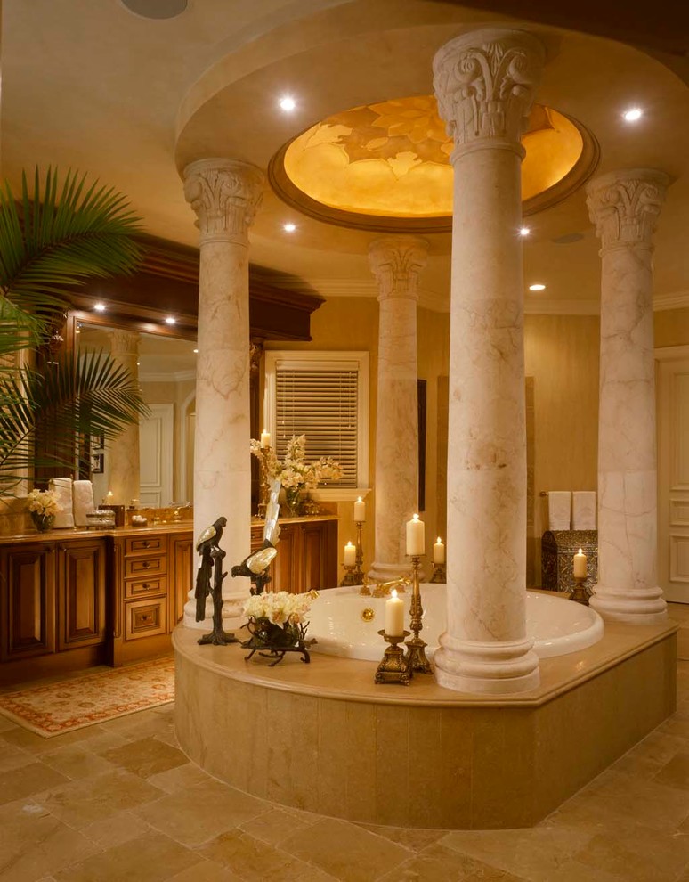 Expansive mediterranean master bathroom in Miami with raised-panel cabinets, medium wood cabinets, marble benchtops, a drop-in tub, an open shower, a one-piece toilet, beige tile and stone slab.