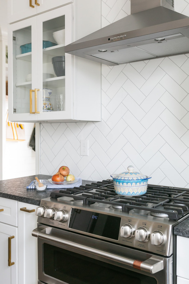 Large transitional l-shaped brown floor kitchen pantry photo in Baltimore with a drop-in sink, shaker cabinets, white cabinets, quartz countertops, white backsplash, ceramic backsplash, stainless steel appliances, an island and white countertops