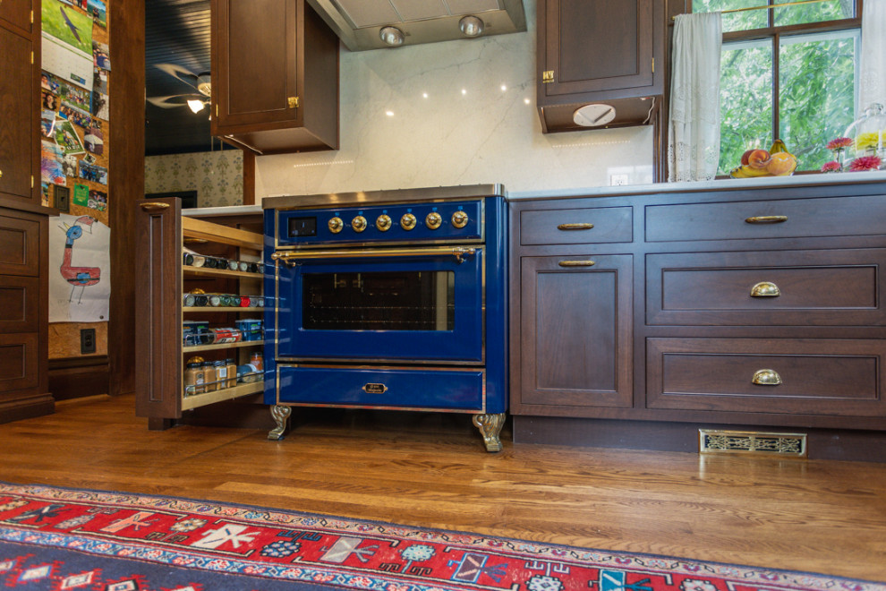Large ornate u-shaped dark wood floor and brown floor kitchen pantry photo in Cincinnati with a drop-in sink, glass-front cabinets, dark wood cabinets, granite countertops, white backsplash, stone slab backsplash, stainless steel appliances and white countertops