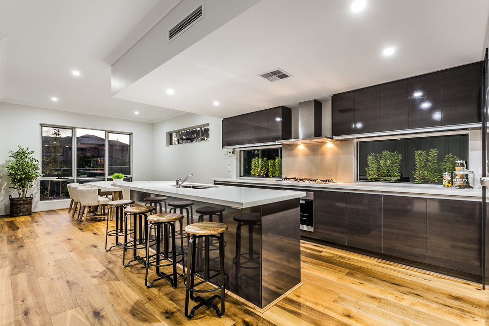 Inspiration for a contemporary galley open plan kitchen in Perth with a double-bowl sink, flat-panel cabinets, black cabinets, stainless steel appliances, light hardwood floors and with island.