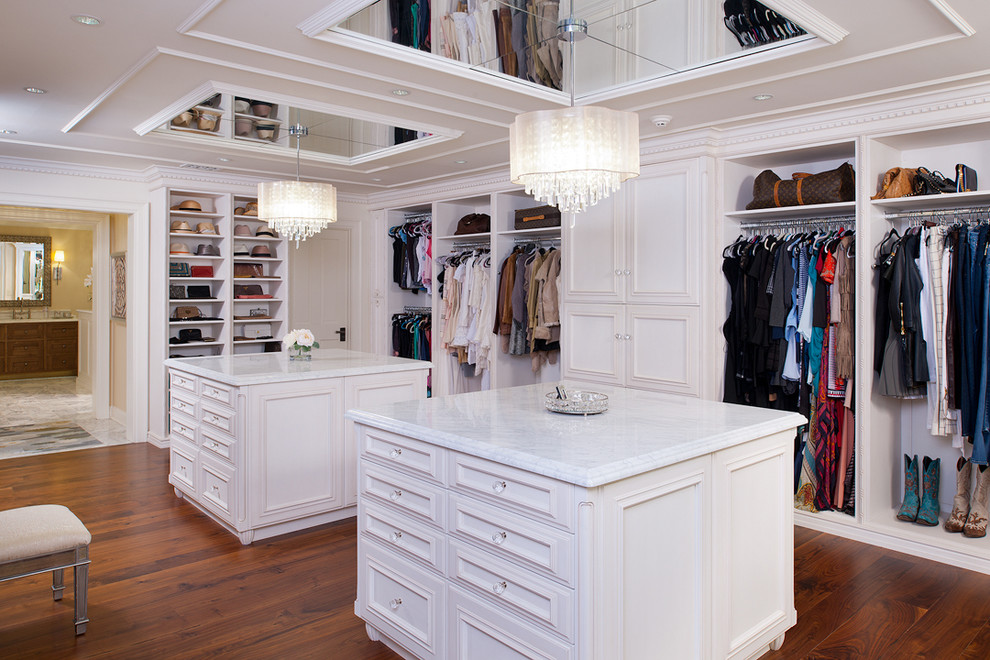 This is an example of an expansive traditional women's dressing room in Other with white cabinets, light hardwood floors and raised-panel cabinets.