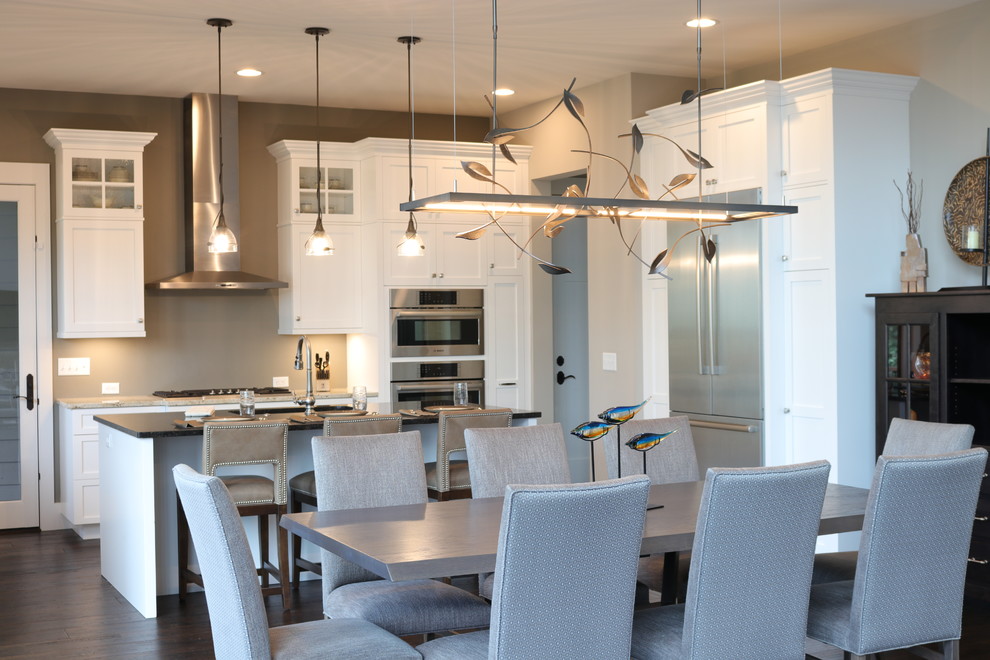 Example of a mid-sized transitional l-shaped dark wood floor and brown floor eat-in kitchen design in Charlotte with a single-bowl sink, shaker cabinets, white cabinets, granite countertops, beige backsplash, stone tile backsplash, stainless steel appliances, an island and brown countertops