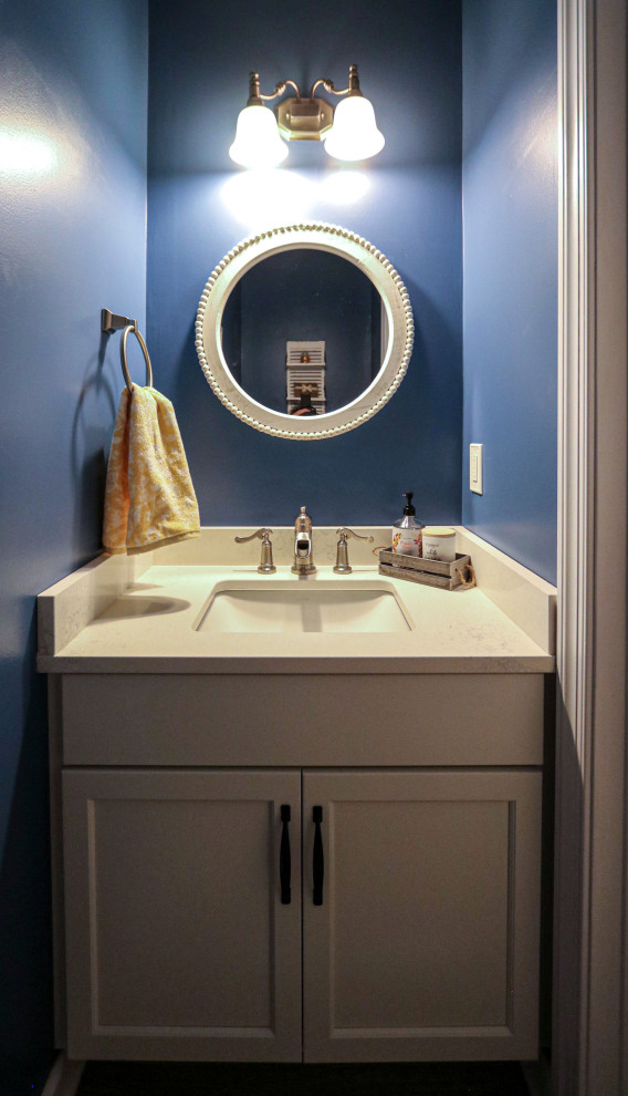 This is an example of a small transitional powder room in Cleveland with flat-panel cabinets, white cabinets, blue walls, medium hardwood floors, engineered quartz benchtops, brown floor, white benchtops and a freestanding vanity.