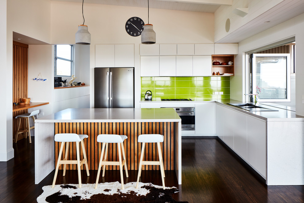 Inspiration for a contemporary l-shaped open plan kitchen in Sydney with a drop-in sink, flat-panel cabinets, white cabinets, green splashback, stainless steel appliances, dark hardwood floors, with island and brown floor.