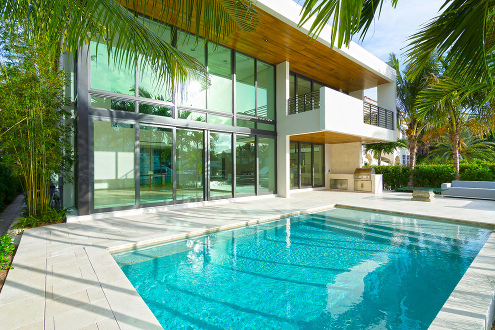 Design ideas for a tropical backyard rectangular pool in Miami with concrete pavers.