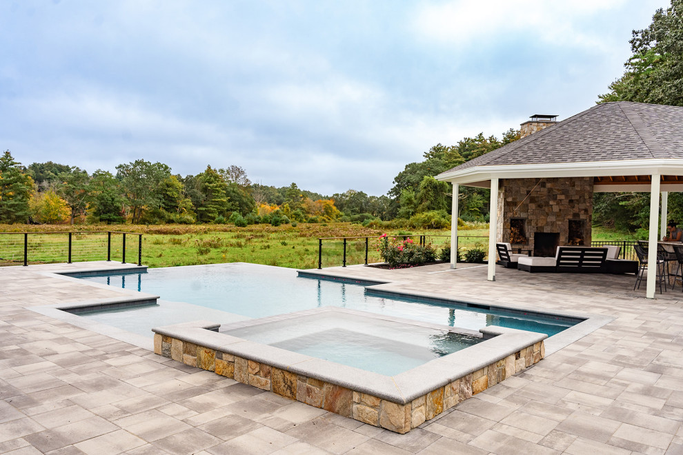 Large trendy stone and custom-shaped infinity pool landscaping photo in Boston