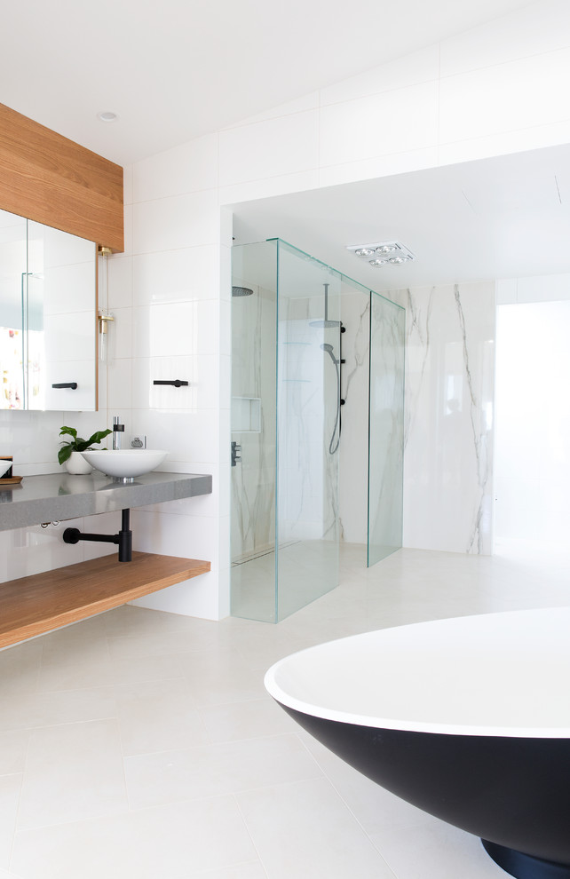 This is an example of a large contemporary master bathroom in Gold Coast - Tweed with flat-panel cabinets, light wood cabinets, a freestanding tub, a double shower, a one-piece toilet, white tile, porcelain tile, white walls, porcelain floors, a vessel sink, engineered quartz benchtops, beige floor and an open shower.