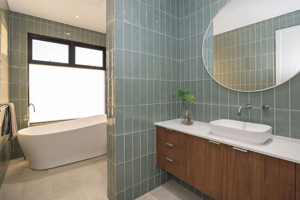 Photo of a contemporary master bathroom in Perth with flat-panel cabinets, medium wood cabinets, a freestanding tub, gray tile, a vessel sink, beige floor and white benchtops.