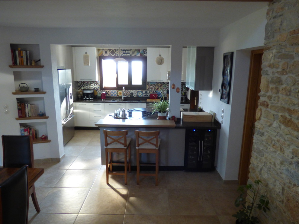 Example of a small mountain style u-shaped ceramic tile eat-in kitchen design with an integrated sink, flat-panel cabinets, white cabinets, quartz countertops, multicolored backsplash, cement tile backsplash, stainless steel appliances and an island